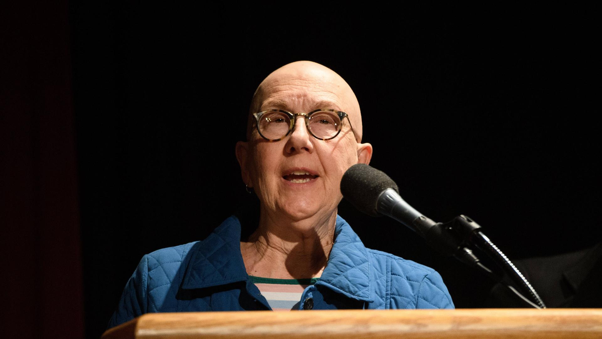 Die Dokumentarfilmerin Julia Reichert trägt eine Brille und steht hinter einem Rednerpult.