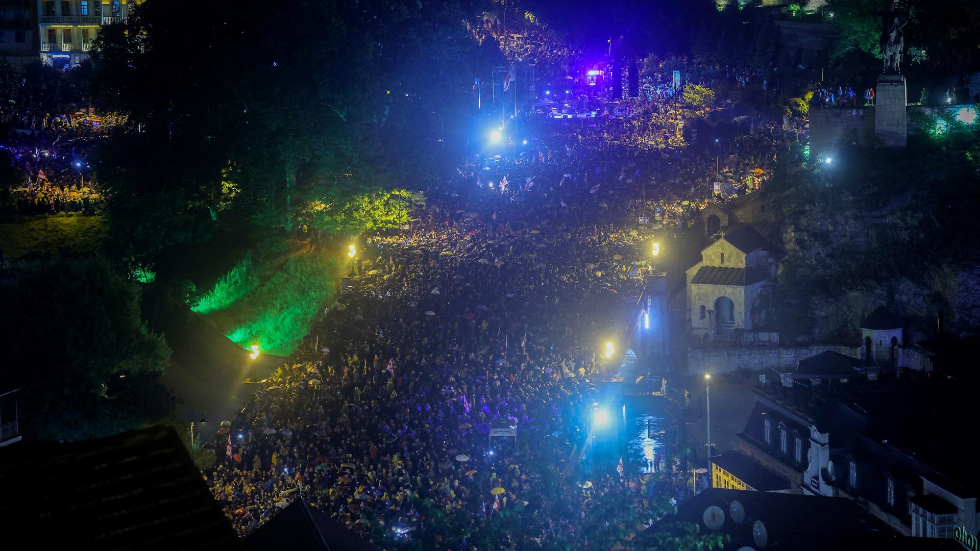 Zu sehen ist eine große Menschenmenge in Georgiens Hauptstadt Tiflis im abendlichen Dunkel. 