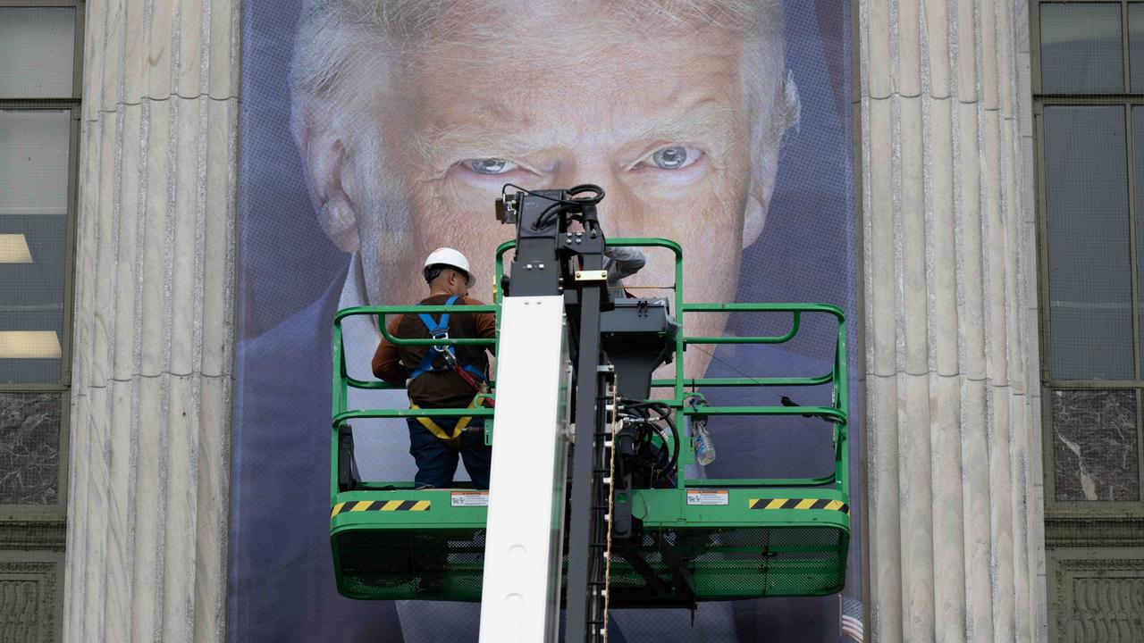 Donald Trump als Plakat. Seine Augen sind hinter einer Plattform zu erkennen, auf der ein Arbeiter steht. Vermutlich bringt dieser gerade das überlebensgroße Banner an