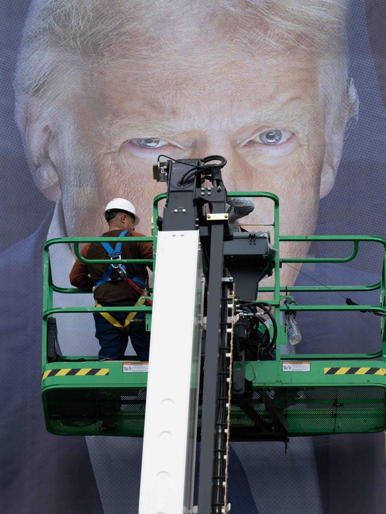 Donald Trump als Plakat. Seine Augen sind hinter einer Plattform zu erkennen, auf der ein Arbeiter steht. Vermutlich bringt dieser gerade das überlebensgroße Banner an