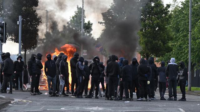 Schwarz vermummte Jugendliche versammeln sich am 9. Juni 2026 in Belfast, Nordirland, vor einer brennenden Barrikade in den Duncairn Gardens.