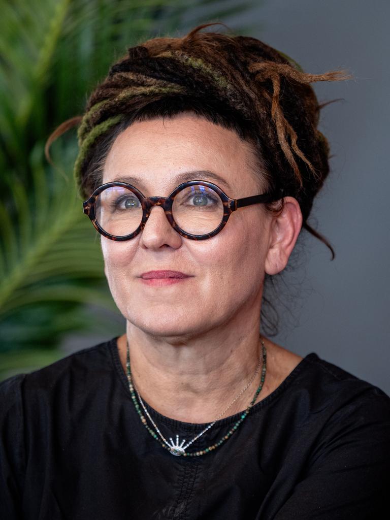Olga Tokarczuk trägt eine runde, schwarz umrandete Brille und ein schwarzes Oberteil. Sie schaut zur Seite und lächelt.