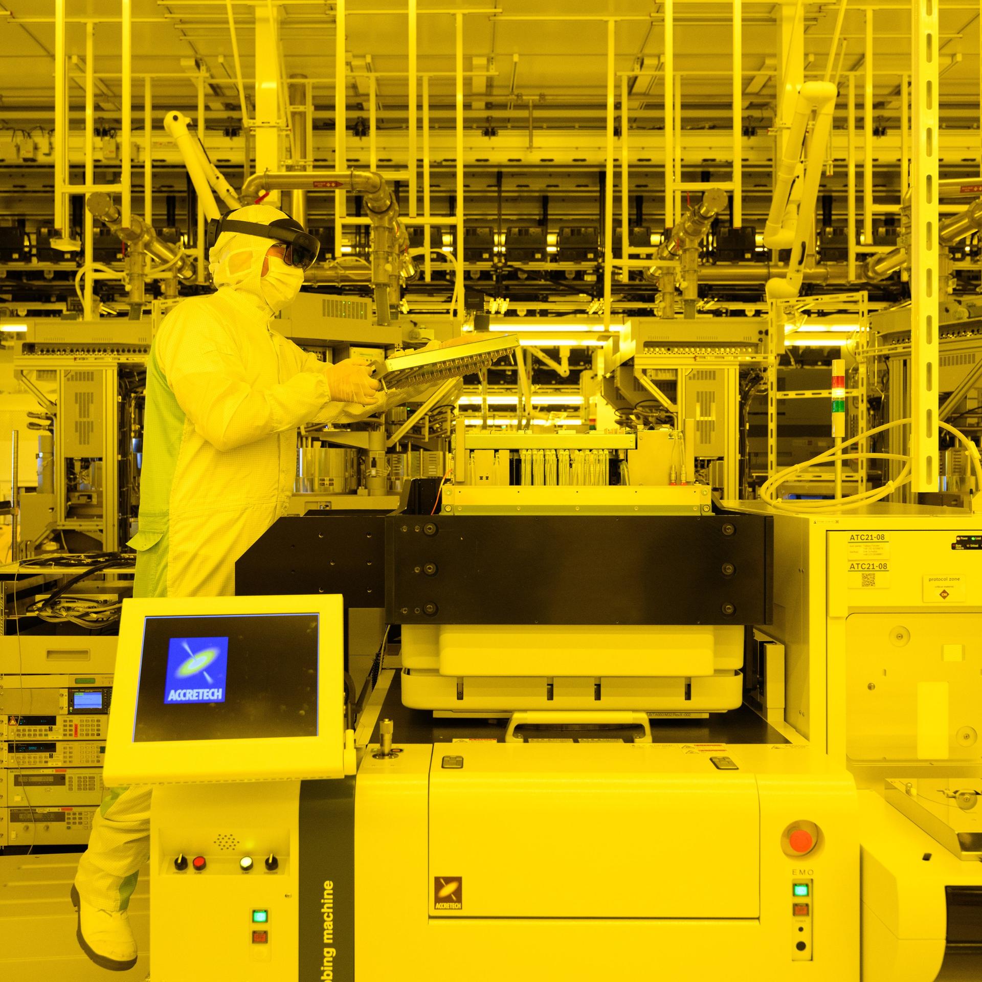 Ein Mitarbeiter demonstriert in der Halbleiterfabrik von Bosch die Wartungsarbeiten an einer Prüfmaschine für Chips mit Augmented-Reality-Brille.