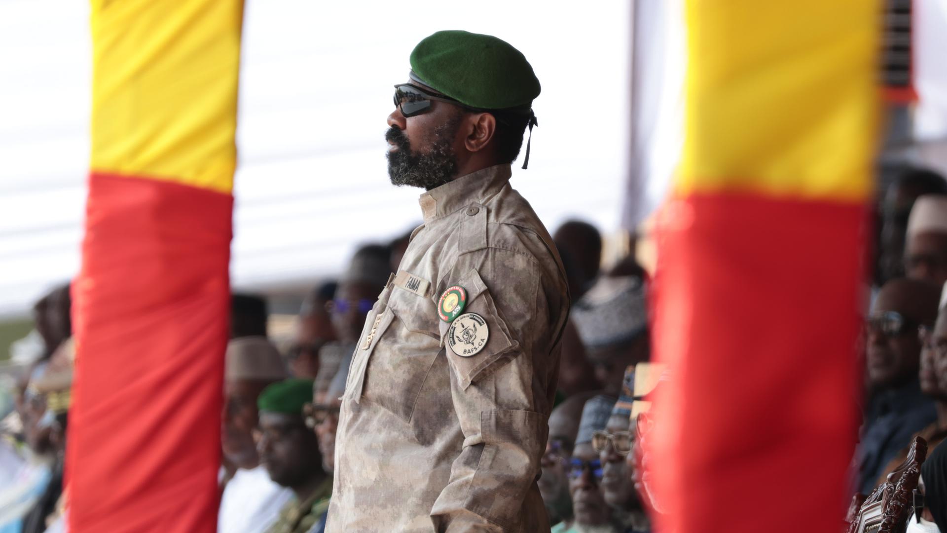 Malis Junta-Chef General Assimi Goita steht in Uniform und mit Sonnenbrille zwischen zwei Pfosten in den Nationalfarbe Malis