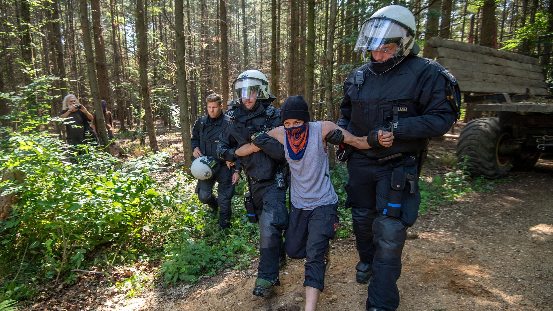 Polizisten führen im Sommer 2020 im Hambacher Wald eine Umweltaktivistin ab. 
