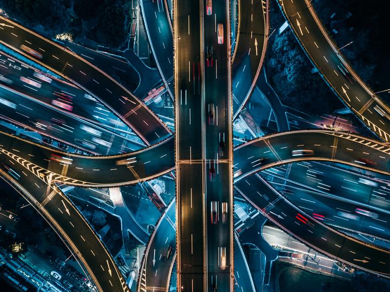 Luftaufnahme sich kreuzender Autobahnstrecken bei Nacht.