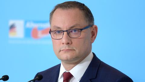 Tino Chrupalla , Co-Vorsitzender der AfD-Fraktion im Bundestag , im Porträt vor einer hellblauen Wand mit AfD-Logo