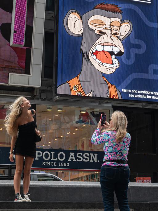 Während der NFT-NYC-Konferenz am 23. Juni 2022 in New York City machen Menschen Fotos von einem Bored Ape Yacht Club NFT-Plakat am Times Square.