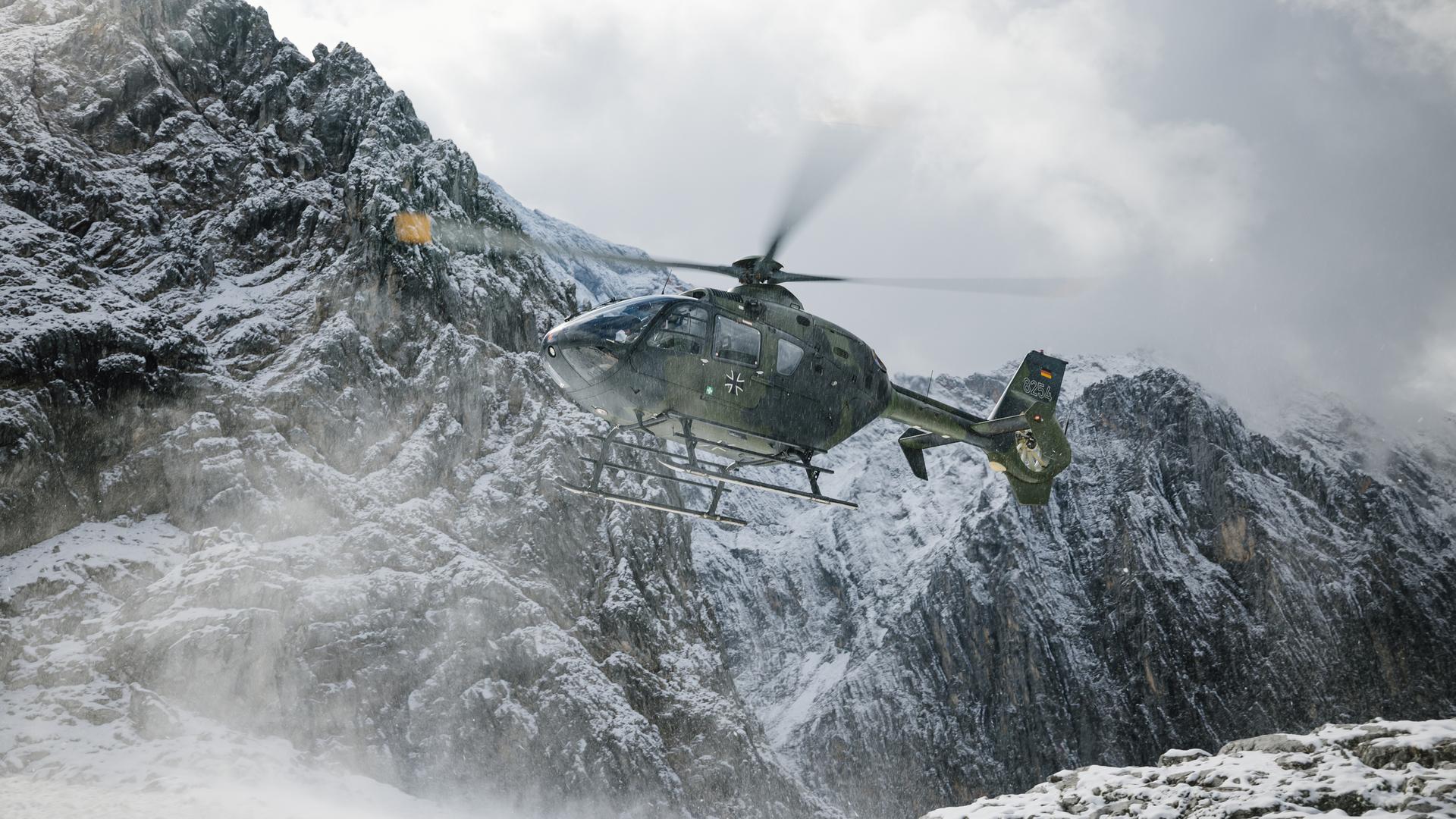 Ein Hubschrauber der Bundeswehr im Flug vor verschneiten Bergen