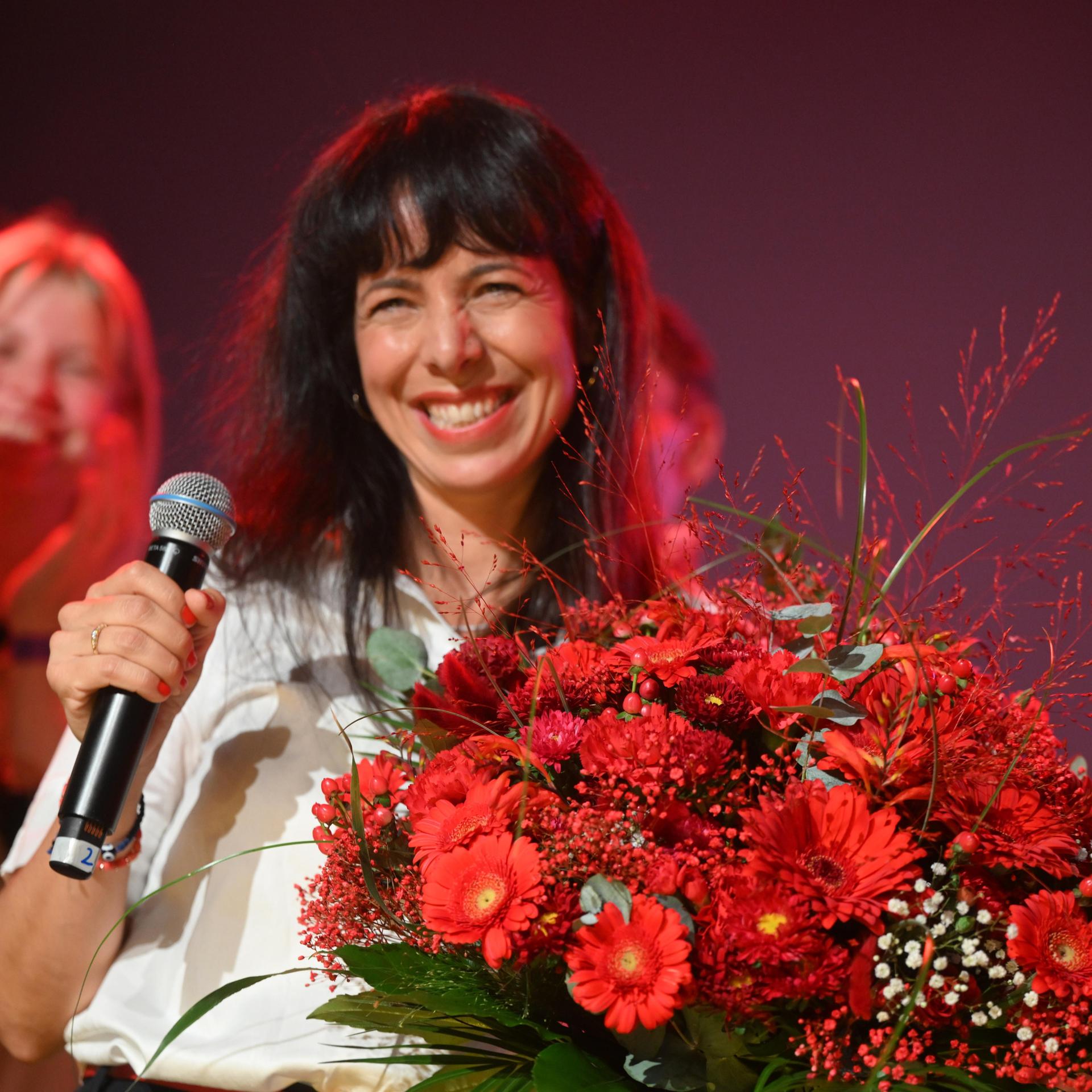 Eine lächelnde Elif Eralp bei der Wahlparty der Linken zur Wahl des Berliner Abgeordnetenhauses mit einem Blumenstrauß in Händen.