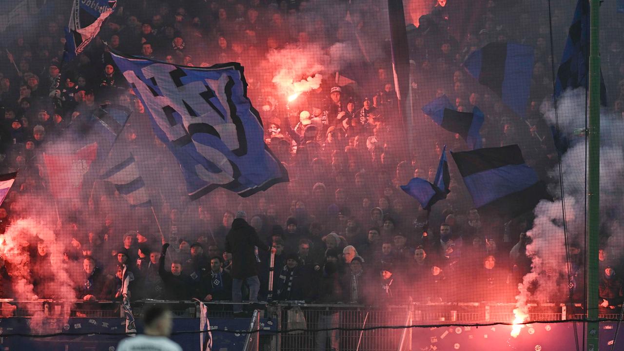 Blick auf den Fanblock des HSV. An mehreren Stellen zünden Fans Pyrotechnik.