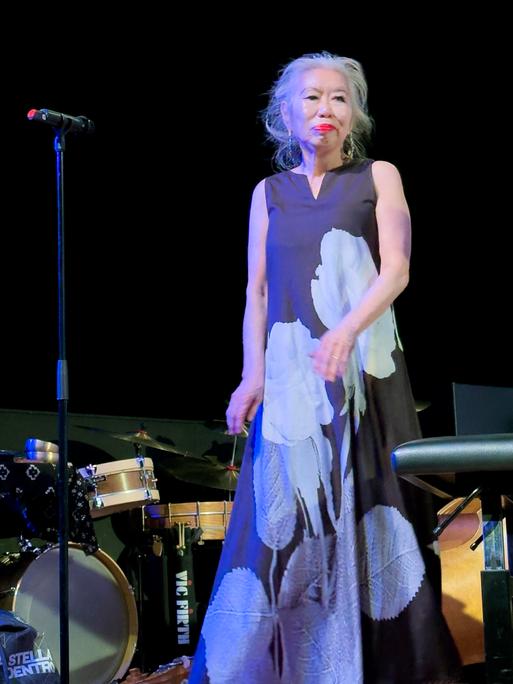 Die japanische Jazzmusikerin Aki Takase steht auf einer Bühne.