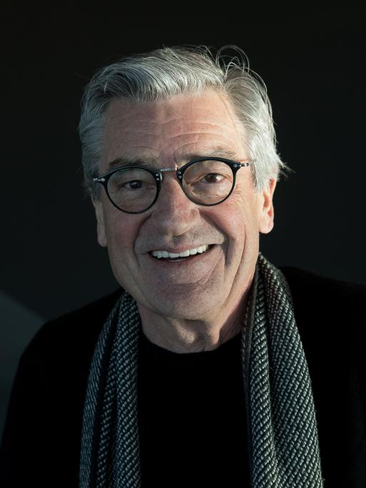 Porträt des lächelnden Dokumentarfilmers Franz Xaver Gernstl, er hat graue Haare und trägt einen Schal über einem schwarzen Pullover