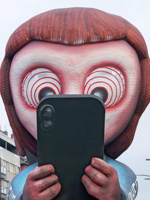Kind starrt mit großen Augen aufs Handy (Mottowagen von Wagenbauer Jacques Tilly, Düsseldorfer Rosenmontagszug) Kind starrt mit großen Augen aufs Handy (Mottowagen von Wagenbauer Jacques Tilly, Düsseldorfer Rosenmontagszug)