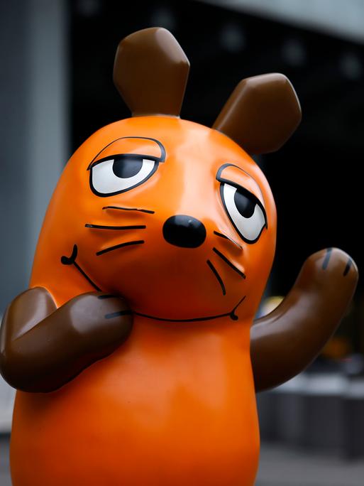 Eine Skulptur von "Die Maus" steht vor dem Gebäude des Westdeutschen Rundfunks in Köln und winkt.