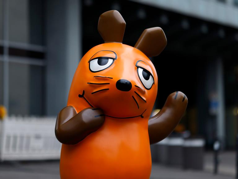 Eine Skulptur von "Die Maus" steht vor dem Gebäude des Westdeutschen Rundfunks in Köln und winkt.