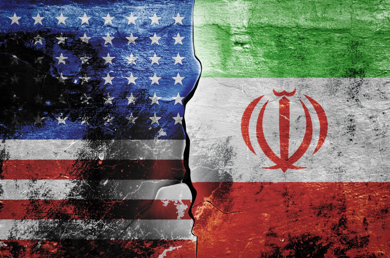 Die Flagge der Vereinigten Staaten von Amerika und die Flagge des Iran vor einem gemusterten Hintergrund