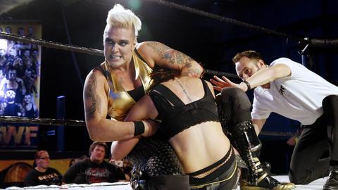 Zwei Wrestlerinnen ringen miteinander auf der einer Bühne.