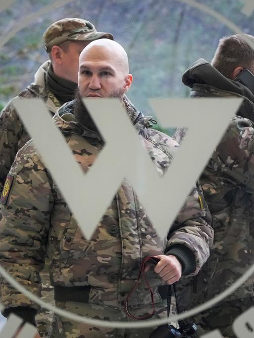 Männer in Camouflage-Anzügen stehen hinter einer Glastür, an der das große "W" der Wagner-Gruppe prangt.