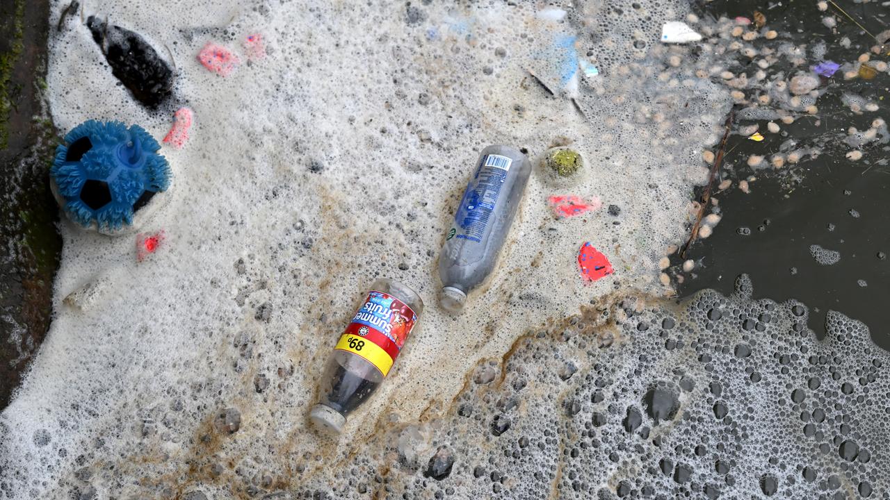 Abfall und Plastikflaschen schwimmen in schmutzigem Schaum im Meer.