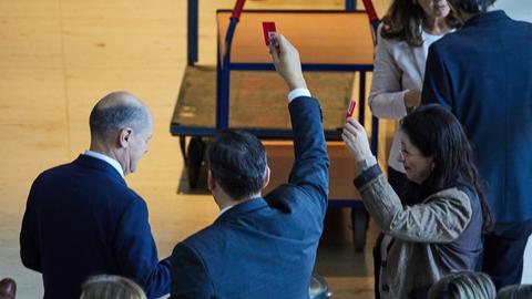 Bundeskanzler Olaf Scholz (l, SPD) gibt bei der 195. Sitzung des Deutschen Bundestages namentlich seine Stimme zum "Sicherheitspaket" ab.