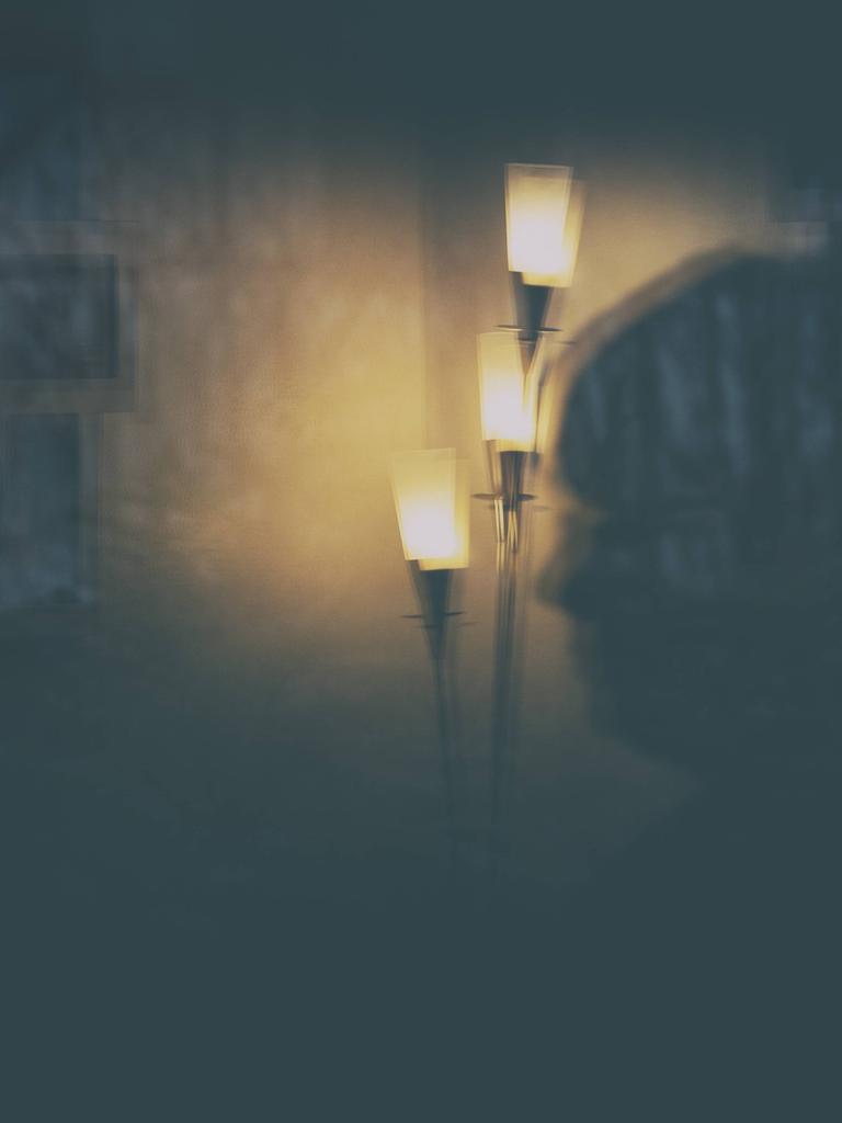 Die Illustration zeigt eine Stehlampe und eine Frau als Spiegelung in einer Glastür nachts