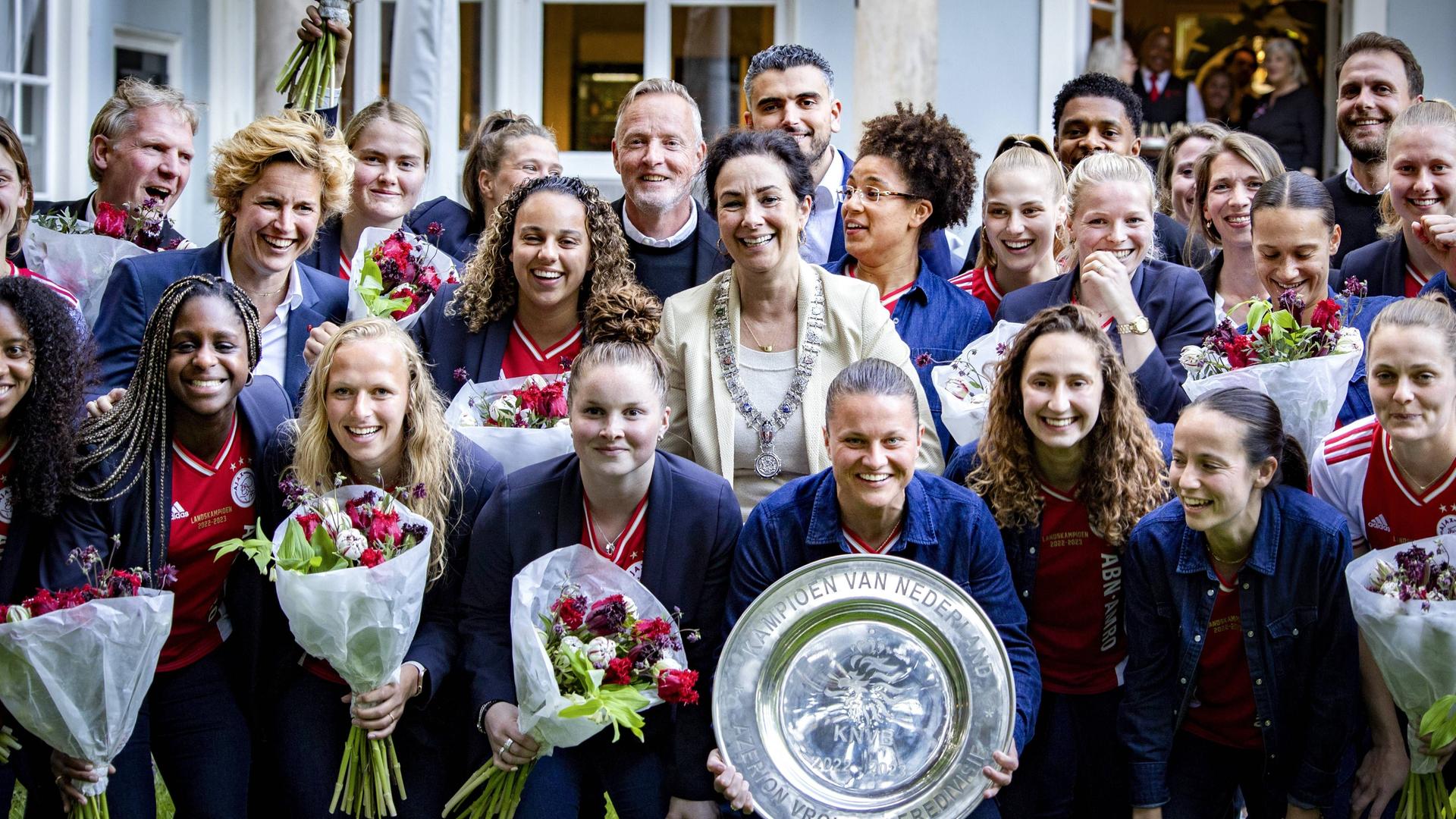 Die Damen-Fußballmannschaft von Ajax Amsterdam steht mit Blumen und der Meisterschale zu einem Gruppefoto zusammen.