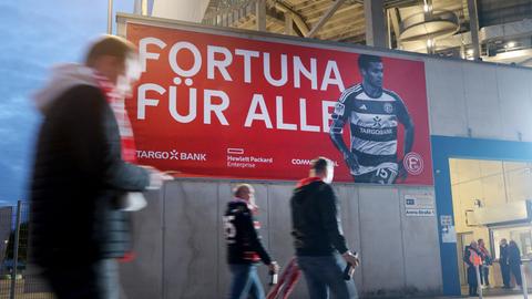 Zuschauer des Spiels Fortuna Düsseldorf gegen Kaiserslautern gehen an einem Transprent vorbei "Fortuna für Alle". Die Tickets für das Spiel sind kostenlos an die Fans abgegeben worden.