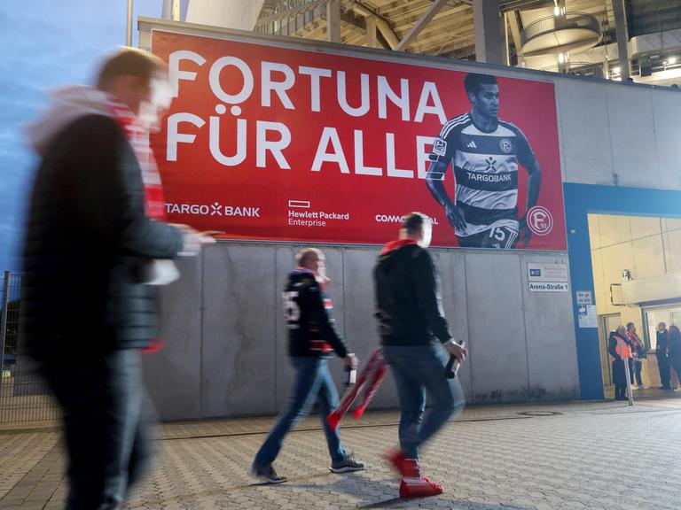 Zuschauer des Spiels Fortuna Düsseldorf gegen Kaiserslautern gehen an einem Transprent vorbei "Fortuna für Alle". Die Tickets für das Spiel sind kostenlos an die Fans abgegeben worden.