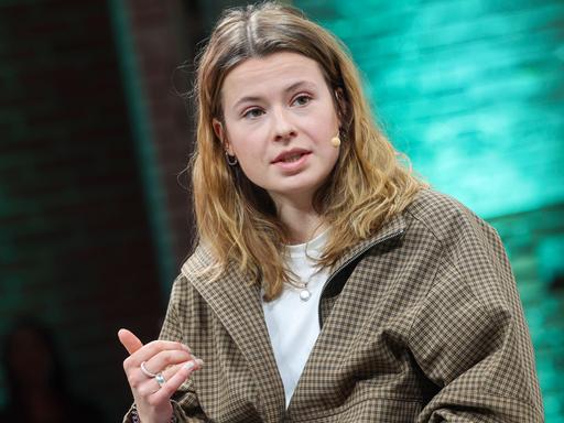 Luisa Neubauer auf Bühne der der Konferenz Re:publica in Berlin. Sie schaut leicht zur Seite, vor ihrem Mund ein Bügelmikrofon. Der Hintergrund schimmert grünlich.
