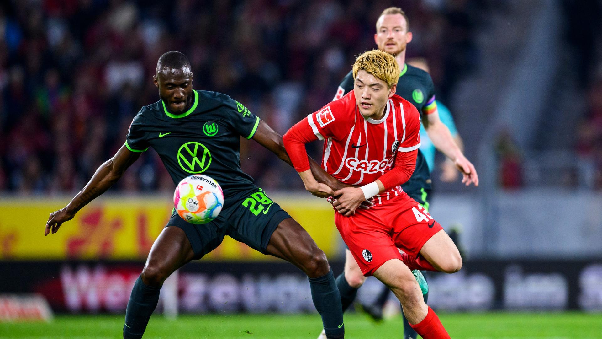 Der Wolfsburger Spieler Guilavogui versucht den Ball gegen den Freiburger Spieler Doan zu verteidigen. Der Wolfsburger Spieler Guilavogui versucht den Ball gegen den Freiburger Spieler Doan zu verteidigen.