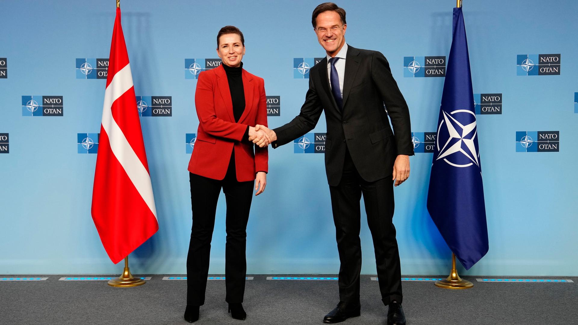 Dänemarks Premierministerin Mette Frederiksen (l) und NATO-Generalsekretär Mark Rutte schütteln sich während ihres Treffens die Hände. Im Hintergrund die NATO- und die dänische Flagge. Dänemarks Premierministerin Mette Frederiksen (l) und NATO-Generalsekretär Mark Rutte schütteln sich während ihres Treffens die Hände. Im Hintergrund die NATO- und die dänische Flagge.
