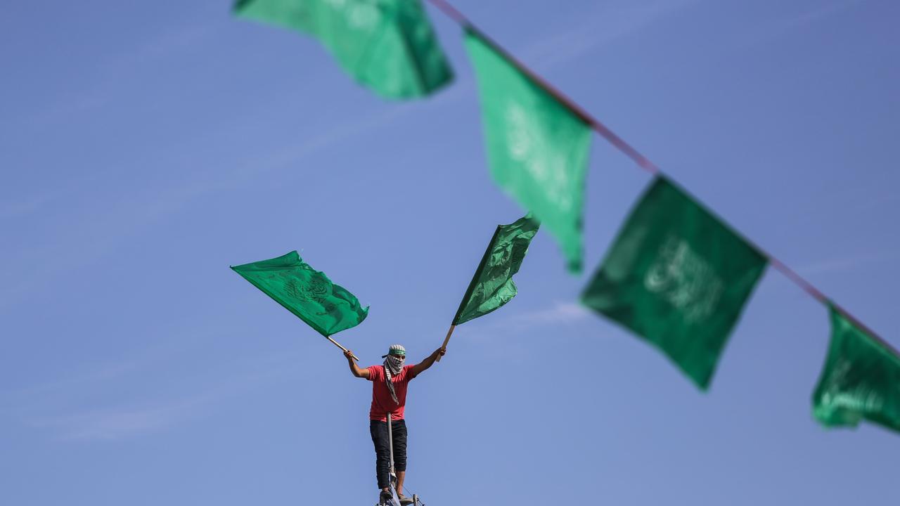 Ein maskierter Hamas-Anhänger schwenkt die Hamas-Flagge. Er nimmt an einer Kundgebung zum 34. Jahrestag der Gründung der islamistischen Bewegung Hamas im Flüchtlingslager Jabalya im nördlichen Gazastreifen teil.