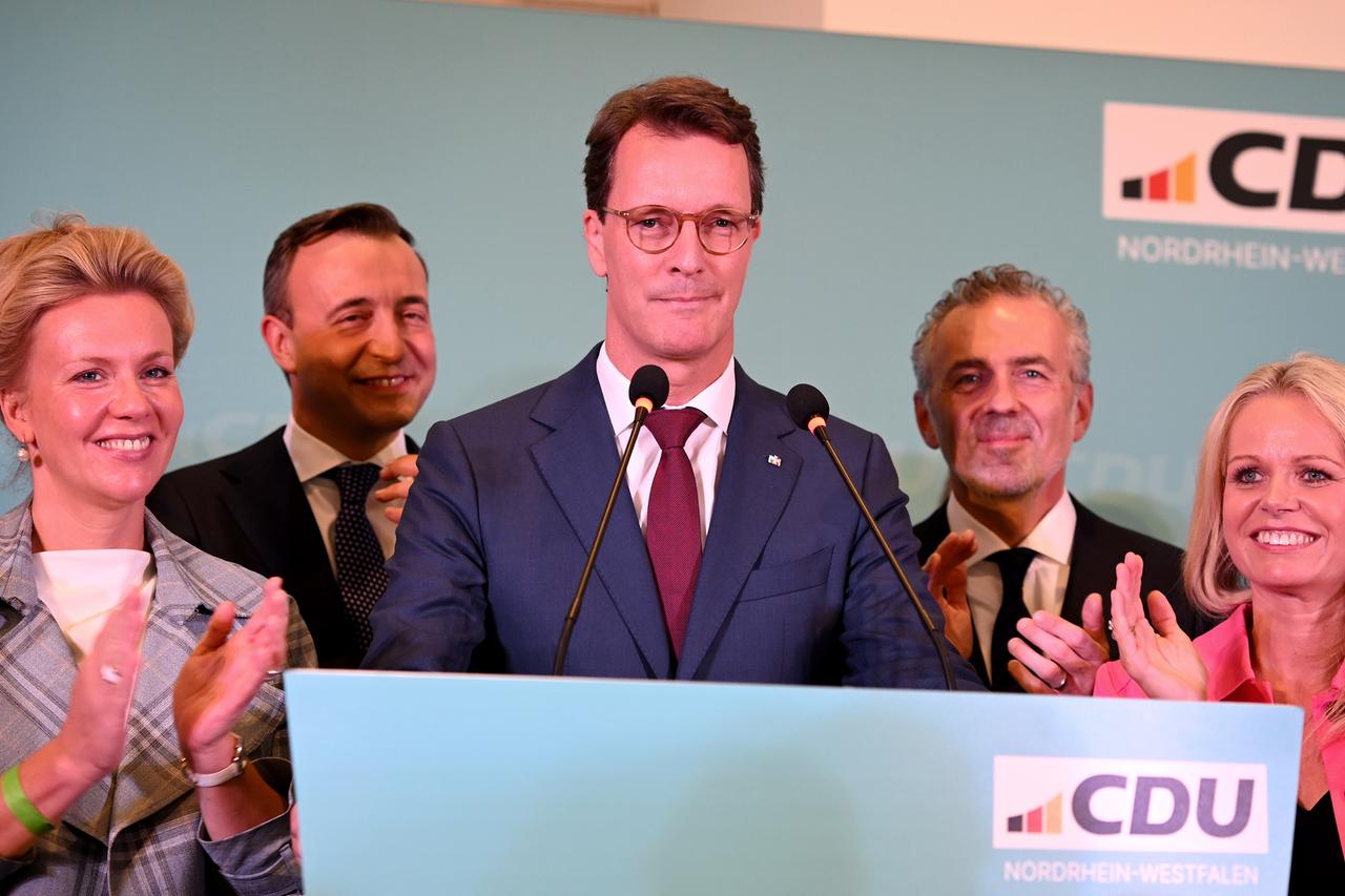 Hendrik Wüst am Rednerpult. Hinter ihm stehen zahlreiche Politiker.