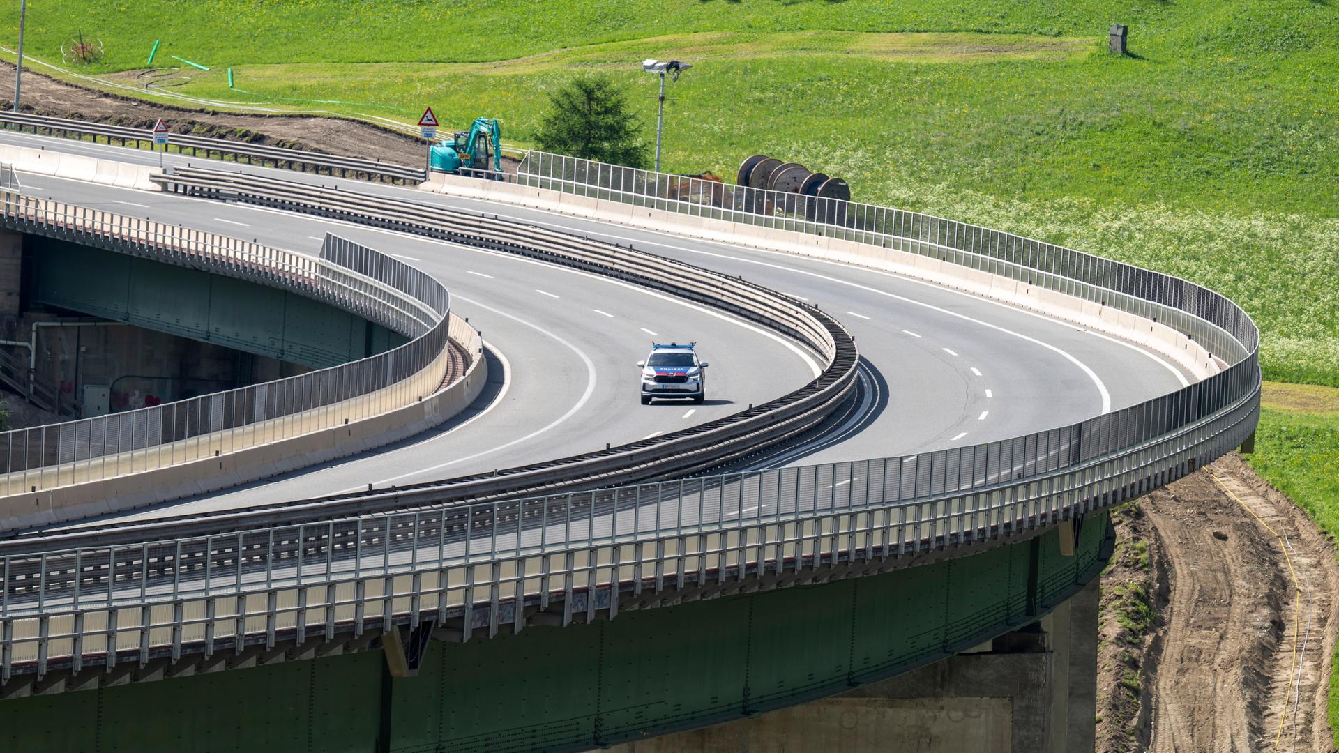 Blick aus der Ferne auf die beiden Fahrspuren auf einer Brückenkurve. Man sieht das Polizeiauto als kleinen Punkt.