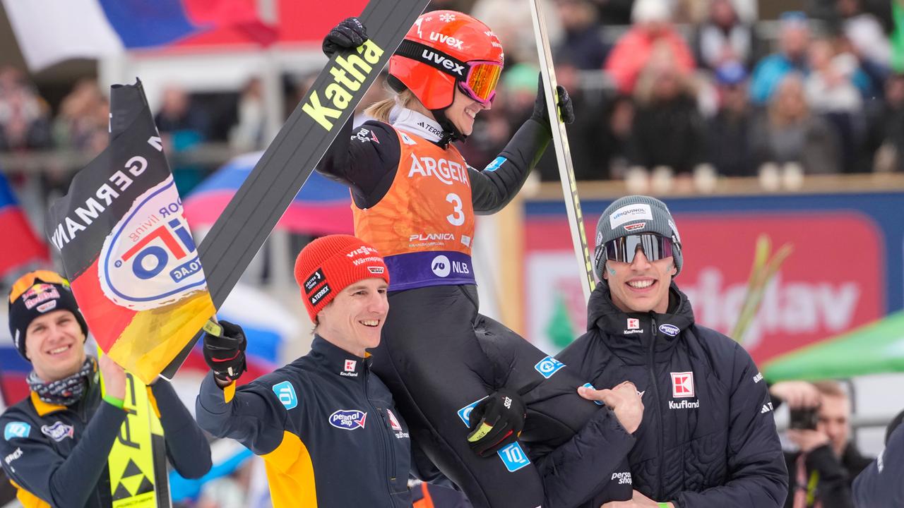 Zwei Skispringer tragen Katharina Schmid auf den Schultern.