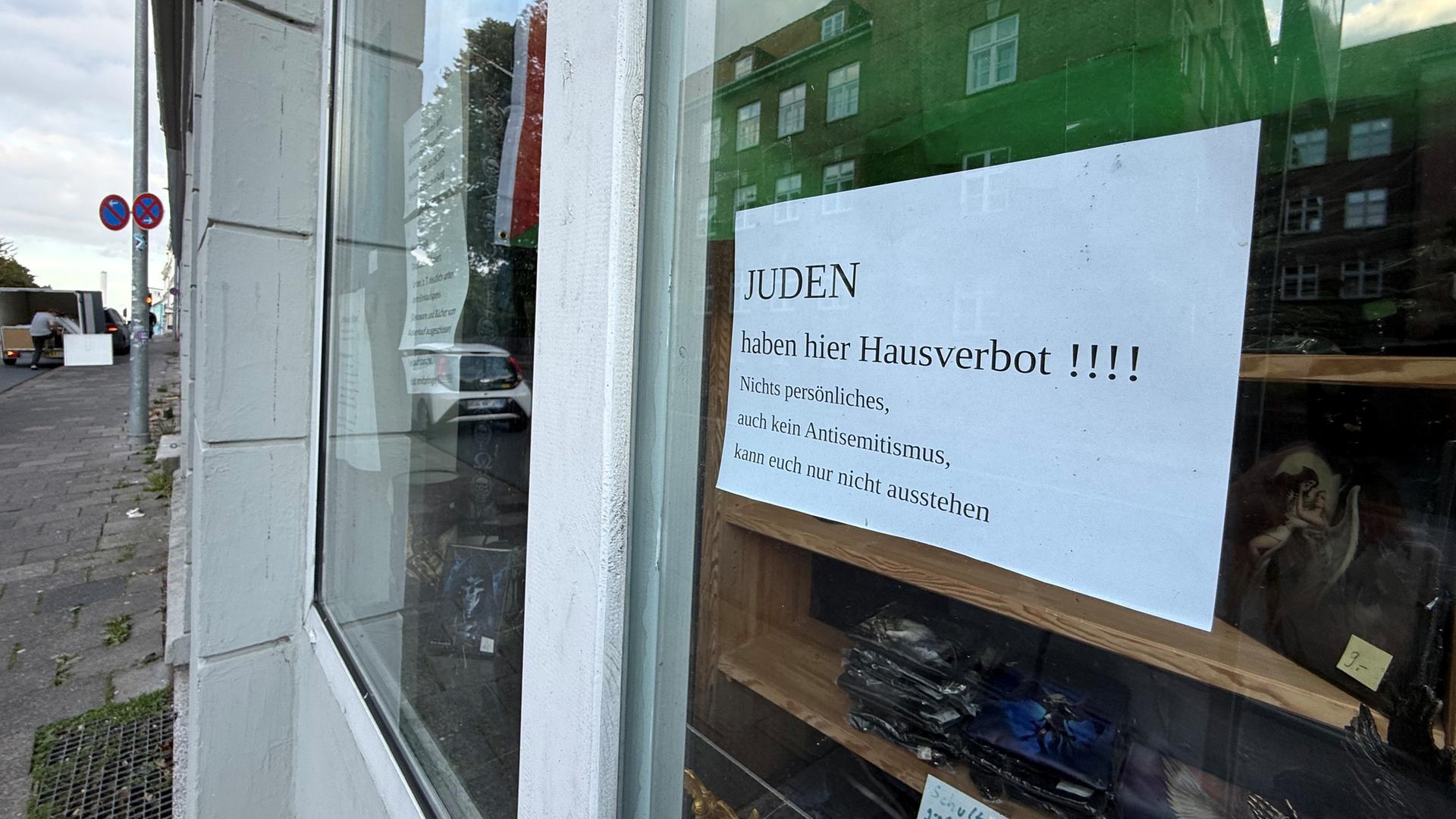 Zu sehen ist ein Stück Papier auf der Innenseite eines Ladenfensters, auf dem zu lesen steht: "Juden haben hier Hausverbot" 