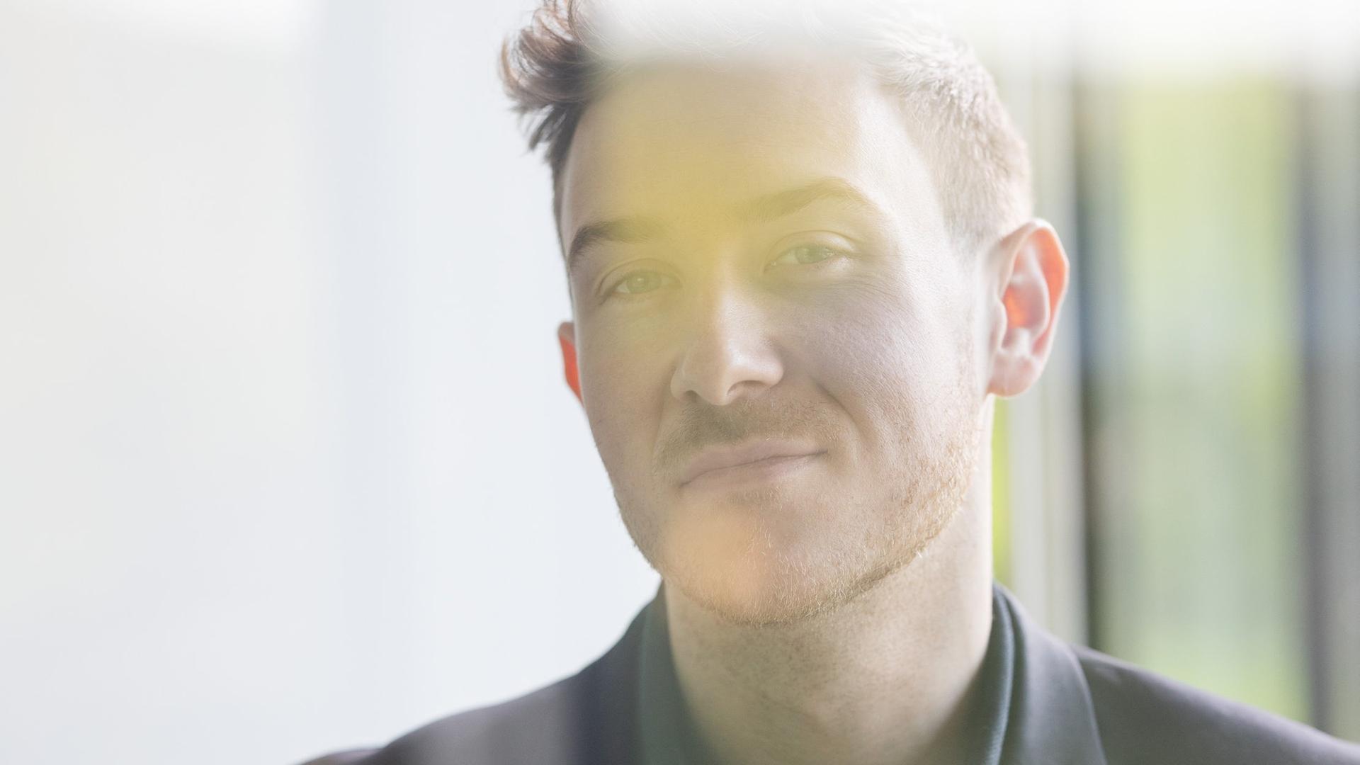 Porträt von Tristan Horx bei dem sich Spiegelungen auf seinem Abbild einzeichnen.