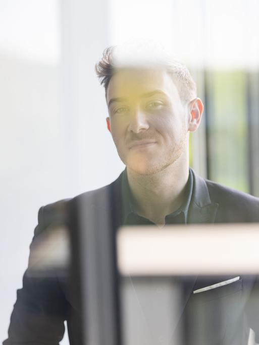 Porträt von Tristan Horx bei dem sich Spiegelungen auf seinem Abbild einzeichnen.