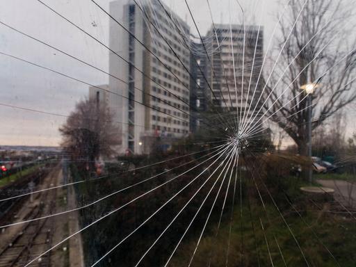 Durch eine Scheibe ist ein Hochhaus in der französischen Vorstadt Nanterre. Die Scheibe ist gesprungen. In Nanterre begannen die Proteste gegen Polizeigewalt nach tödlichen Schüssen auf den 17-Jährigen Nahel.