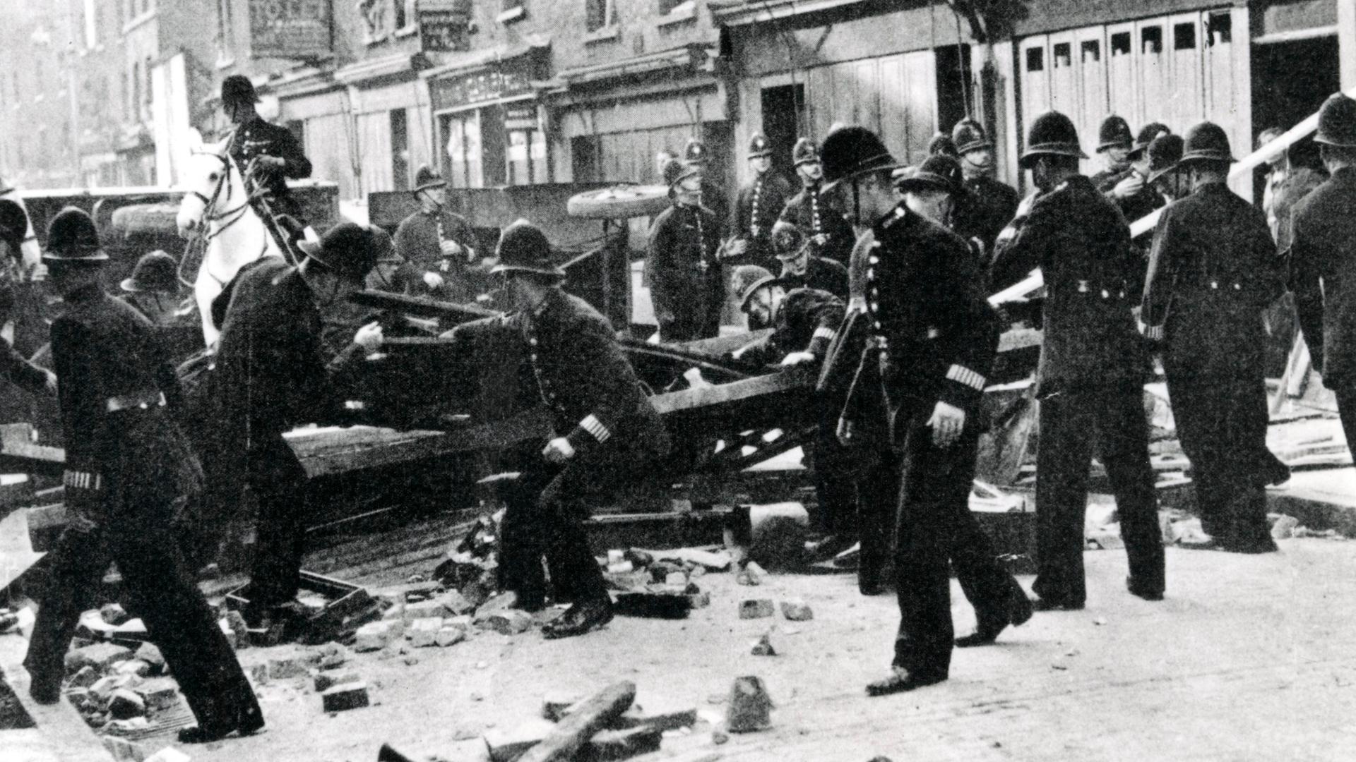 Polizisten räumen zu einer Barrikade aufgerichtetes Geröll von einer Londoner Straße