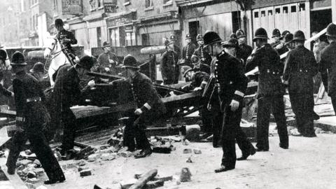 Polizisten räumen zu einer Barrikade aufgerichtetes Geröll von einer Londoner Straße
