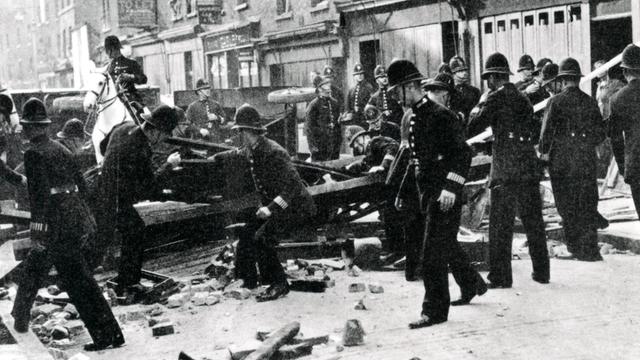 Polizisten räumen zu einer Barrikade aufgerichtetes Geröll von einer Londoner Straße