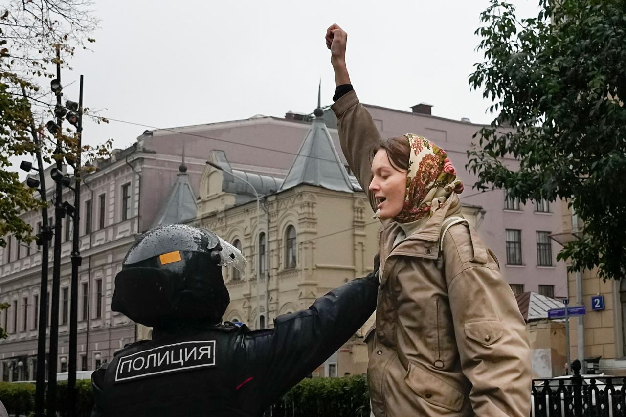 Russland, Moskau: Ein Polizeibeamter hält eine Demonstrantin während einer Demonstration gegen eine Teilmobilisierung fest.