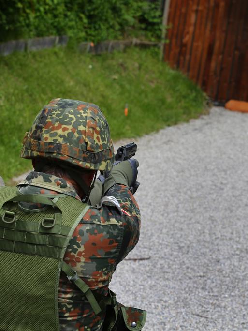 Ein Teilnehmer einer Schießübung der Bundeswehr zielt mit seiner Pistole auf zu treffende "Pappkameraden".