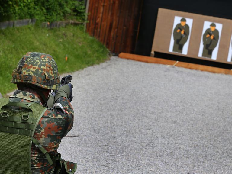 Ein Teilnehmer einer Schießübung der Bundeswehr zielt mit seiner Pistole auf zu treffende "Pappkameraden".