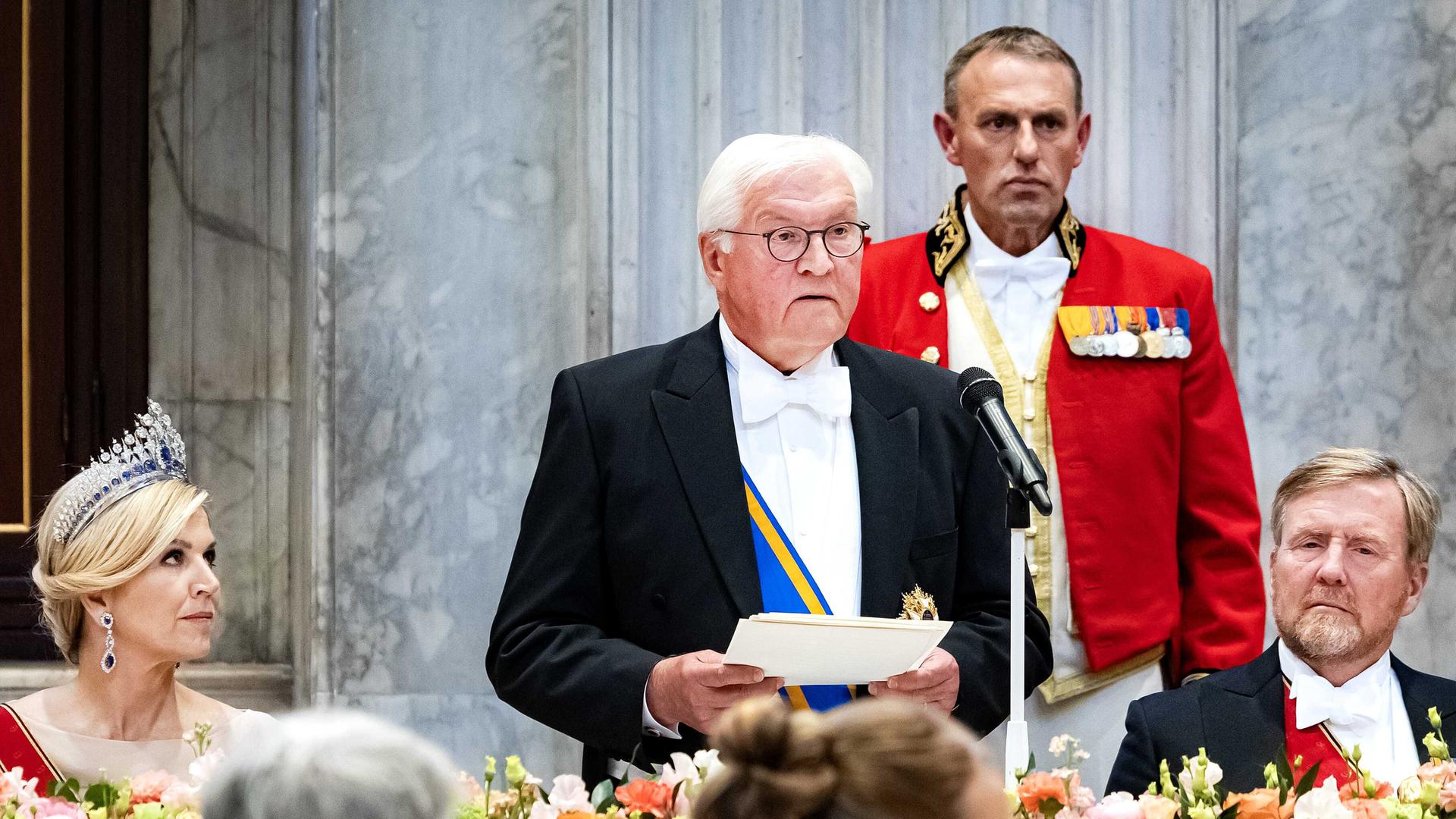 Bundespräsident Frank-Walter Steinmeier steht vor einem Mikrofon. Neben ihm sitzen der niederländische König Willem-Alexander und Königin Máxima.