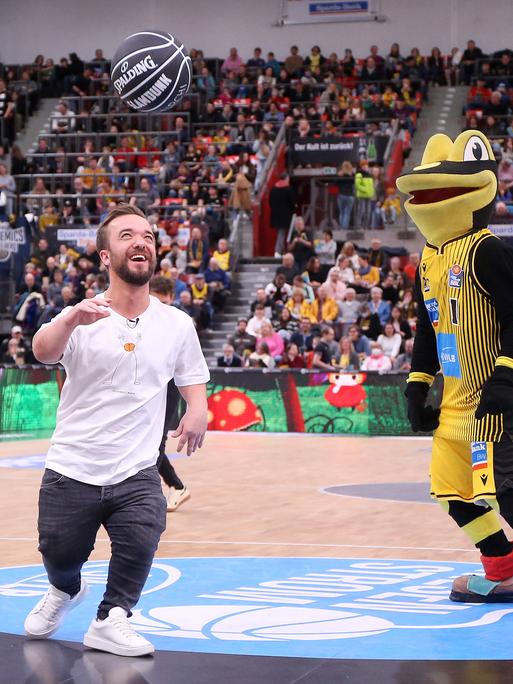 Matthias Mester spielt mit dem Maskottchen Lurchi in Ludwigsburg in einer Halle Basketball.