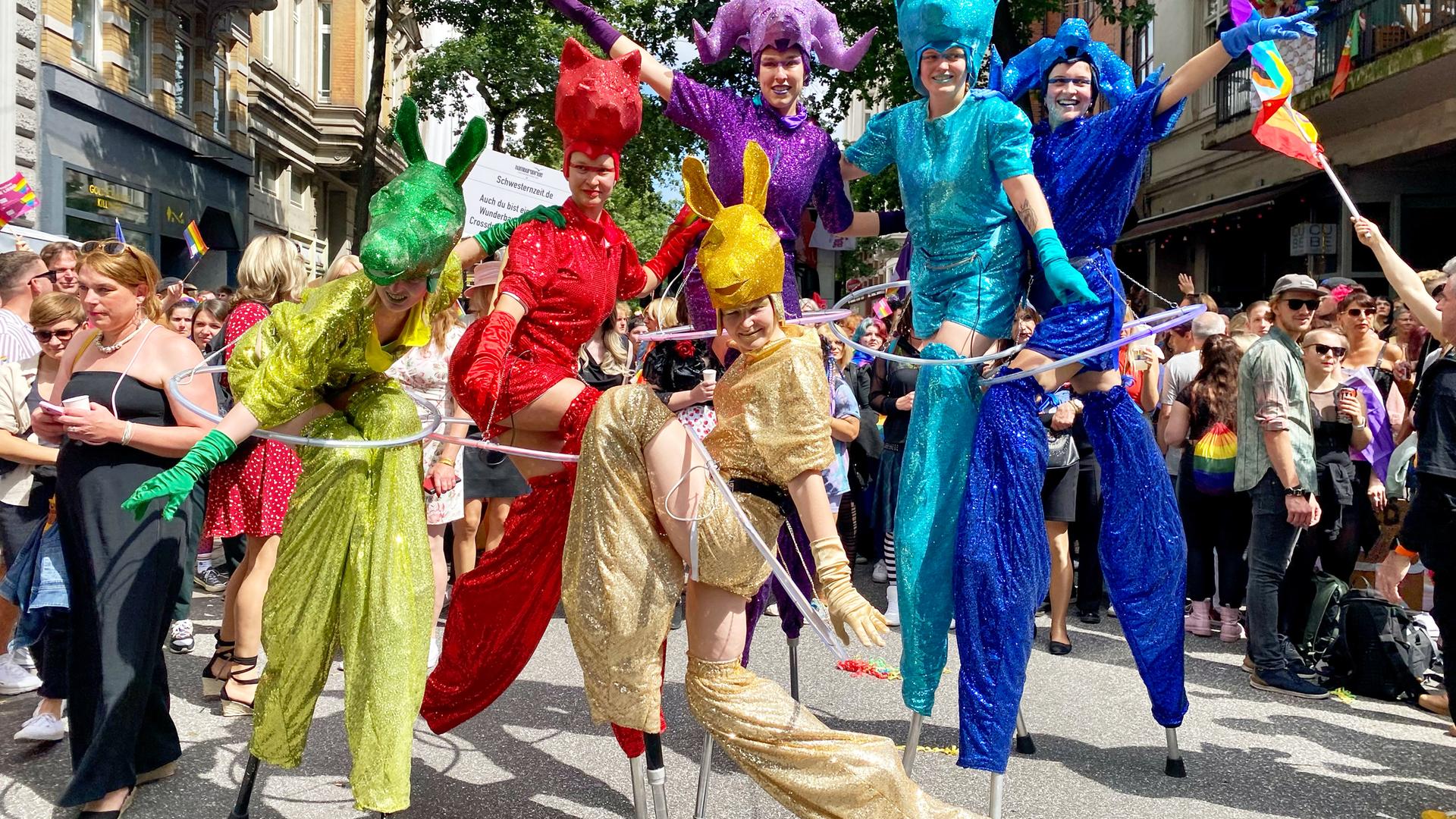 Kostümierte Teilnehmerinnen stehen auf Stelzen während der Parade zum Christopher Street Day.