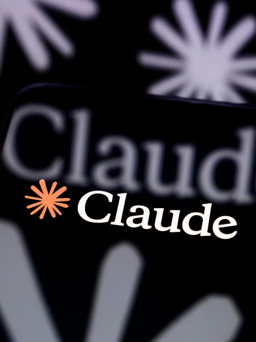 Das Claude-Logo ist auf dem Bildschirm eines Smartphones zu sehen, das auf einer reflektierenden Fläche steht Das Claude-Logo ist auf dem Bildschirm eines Smartphones zu sehen, das auf einer reflektierenden Fläche steht